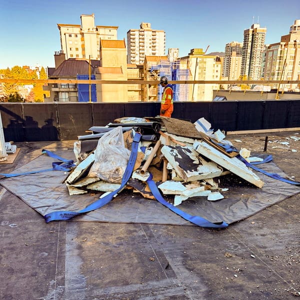 StrongSling loading with a large pile of construction debris on a rooftop jobsite.